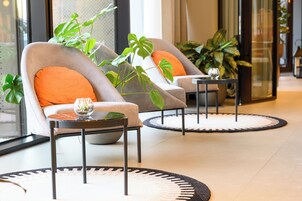 A modern lobby with two armchairs, a small table, and a potted plant.