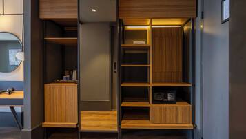 Una habitación compacta y moderna con estanterías de madera integradas, un escritorio y un espejo.