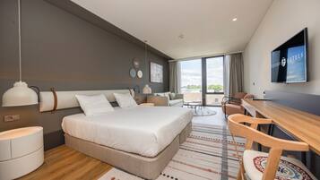 Une chambre d’hôtel moderne, dotée d’un grand lit, d’un bureau et d’une télévision.