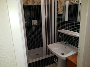 Ein Badezimmer mit Duschkabine, Waschbecken und Spiegel.