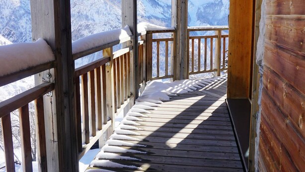 Una terraza de madera con escalones cubiertos de nieve que conducen a una vista de la montaña.