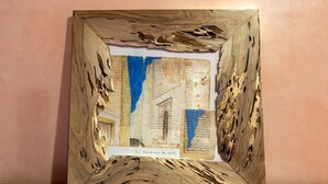 A framed artwork with a rustic wooden frame and a central piece featuring text and drawings. - Private sea view house. (Essaouira)