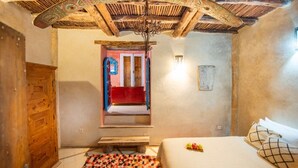A room with a wooden ceiling, a bed with pillows, a red bench, and a patterned rug. - Private sea view house. (Essaouira)