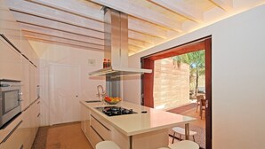 A modern kitchen with a central island, bar stools, and a view of the outdoor patio. - Muralles - Central house with pool, air conditioning, and wifi in Alcúdia (Alcúdia)