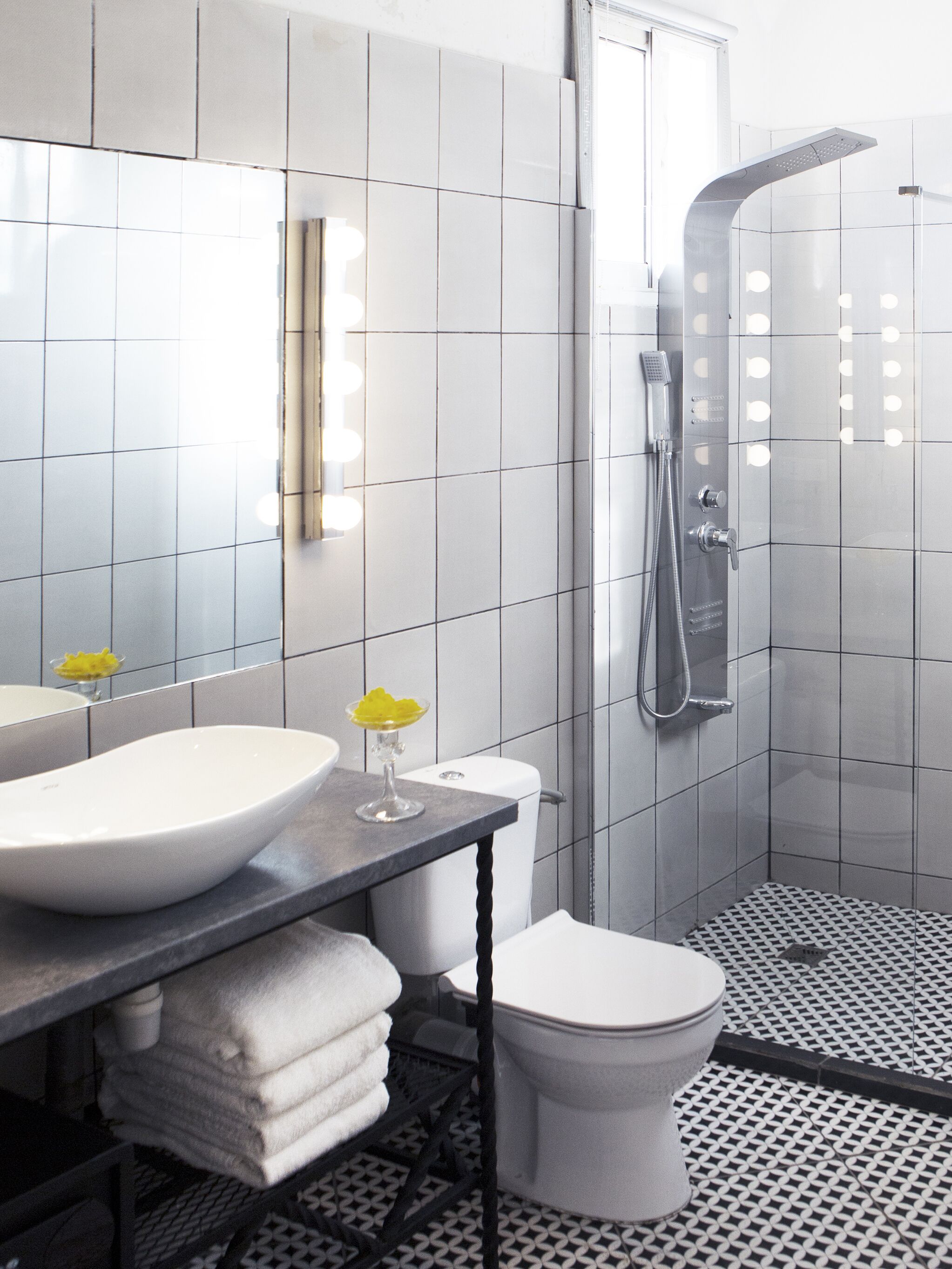 A modern bathroom with a large mirror, a vessel sink, a toilet, and a shower.