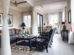 A spacious living room with a patterned rug, a sofa, a striped armchair, and a coffee table. - RoofTop (Serrekunda)