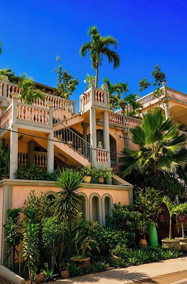 A multi-story hotel with balconies, palm trees, and a well-maintained garden. - RoofTop (Serrekunda)