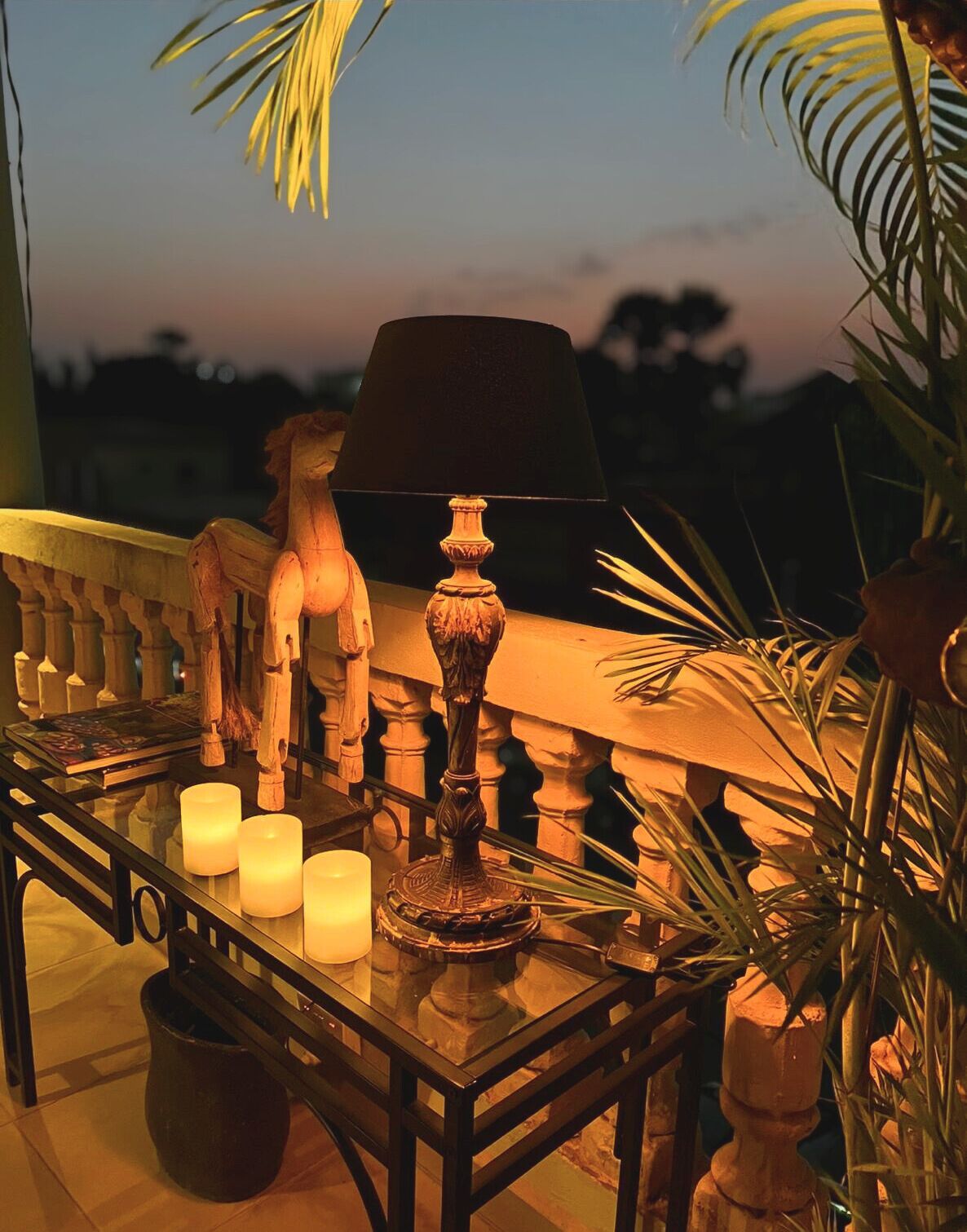 Varanda com mesa, velas, luminária e objetos decorativos.