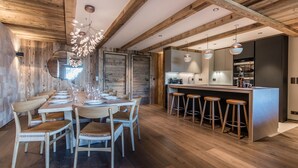 Una cocina moderna con vigas de madera, un comedor con una mesa larga y taburetes de bar.