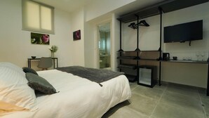 Quarto moderno com uma cama grande, uma escrivaninha e uma televisão.