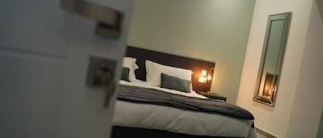 A bedroom with a bed, bedside lamps, and a nightstand.