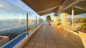 A balcony with a view of the sea, white chairs, and a tiled floor. - Villa Acacia- Spectacular Ocean view & heated pool (Arco Da Calheta)