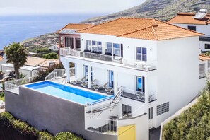 Ein zweistöckiges Gebäude mit Swimmingpool, Balkonen und Meerblick.