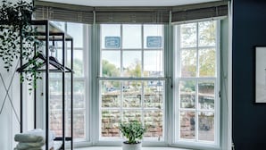 A bay window with a potted plant, a hanging plant, and a towel stack. - Deva Leisure (Chester)