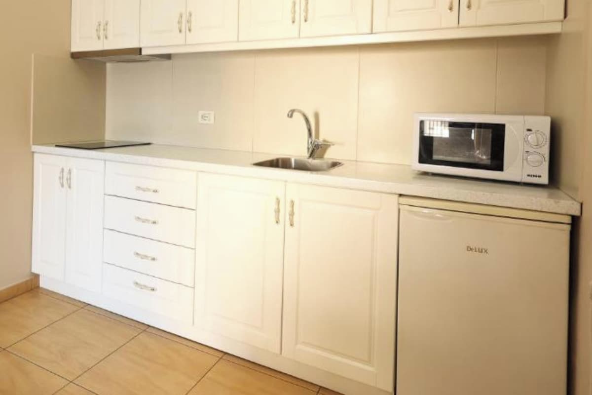A kitchen with white cabinets, a microwave, and a sink.