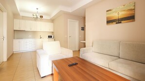 A modern living room with a wooden coffee table, a beige sofa, and a kitchen in the background. - Apartments Flower Residence (Sarandë)