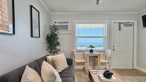 Ett vardagsrum med en grå soffa, ett soffbord i trä och en matplats med ett litet bord och stolar.