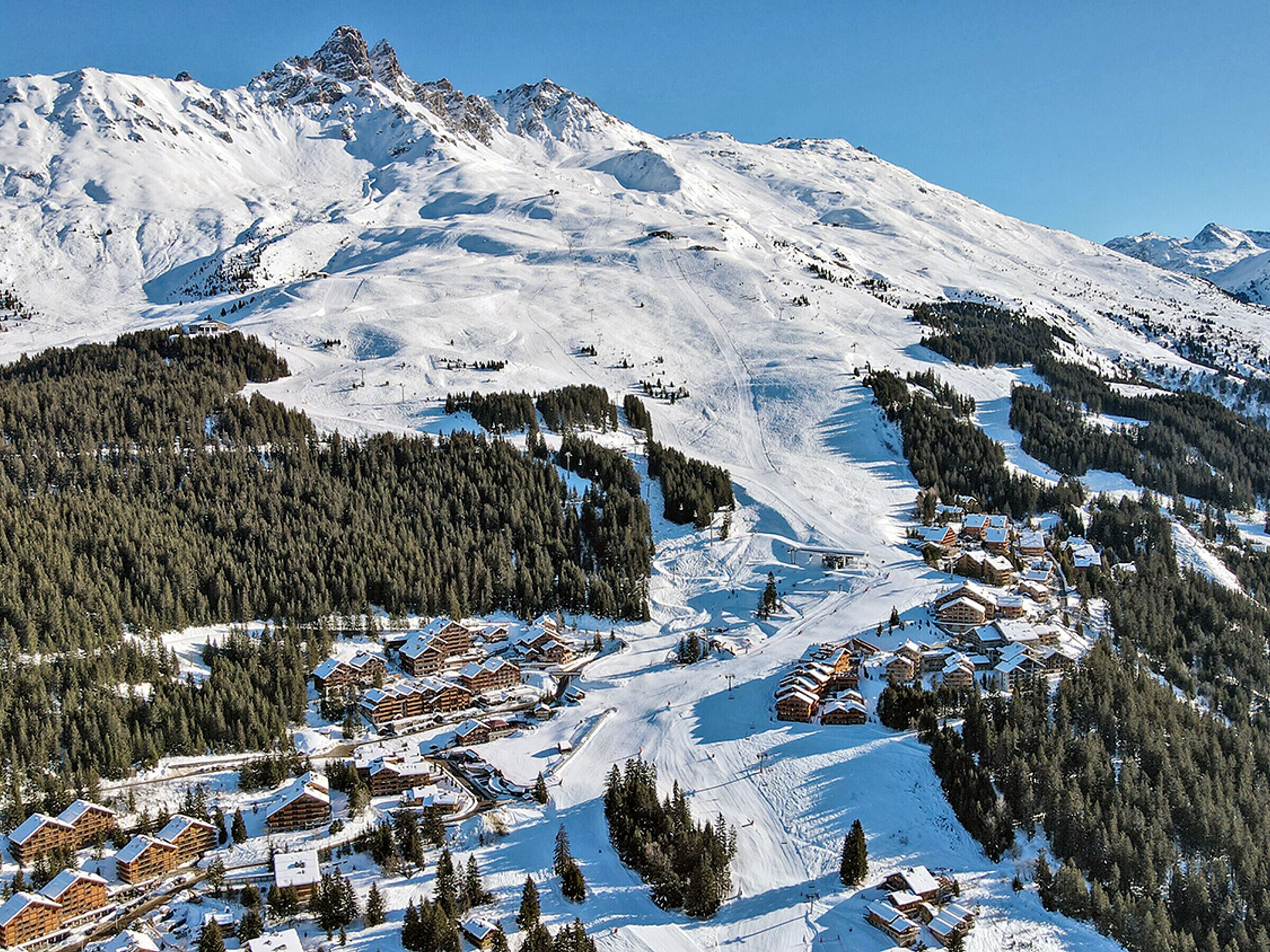 A snow-covered mountain with a ski resort and lodge buildings.