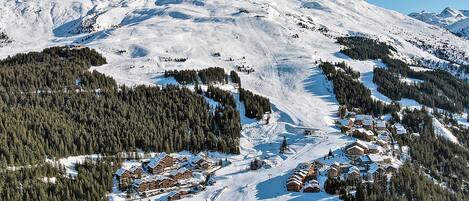 A snow-covered mountain with a ski resort and lodge buildings.