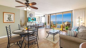 Een ruime woonkamer met een eettafel, stoelen, een bank en een balkon met uitzicht.
