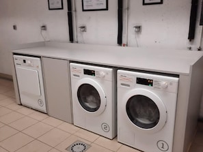 Tre lavatrici bianche a carica frontale disposte in fila, in un ambiente commerciale.