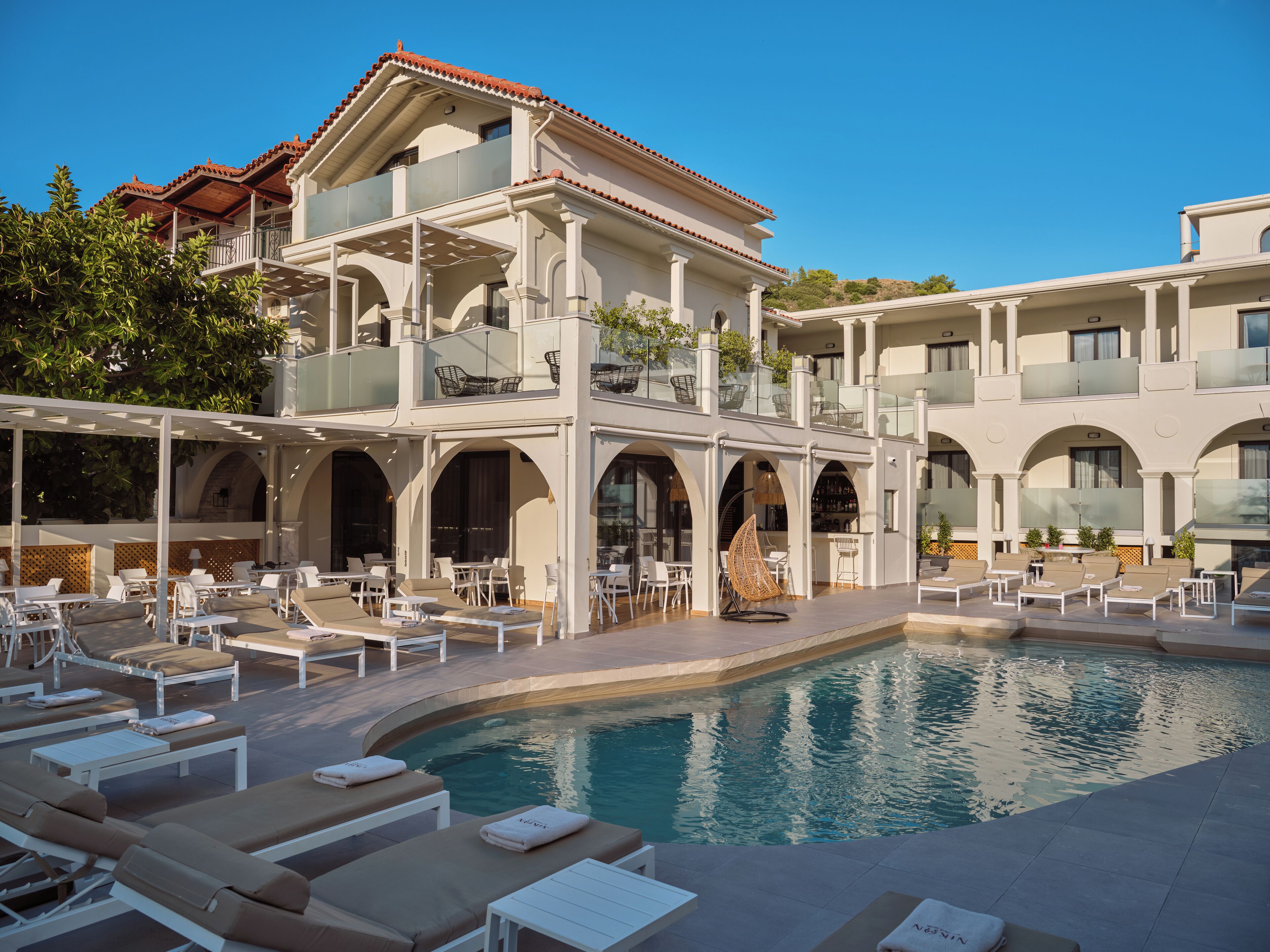 Un área junto a la piscina con sillones de descanso y una piscina.