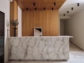 Una reception con piano in marmo, pannelli in legno sopra e illuminazione a incasso.