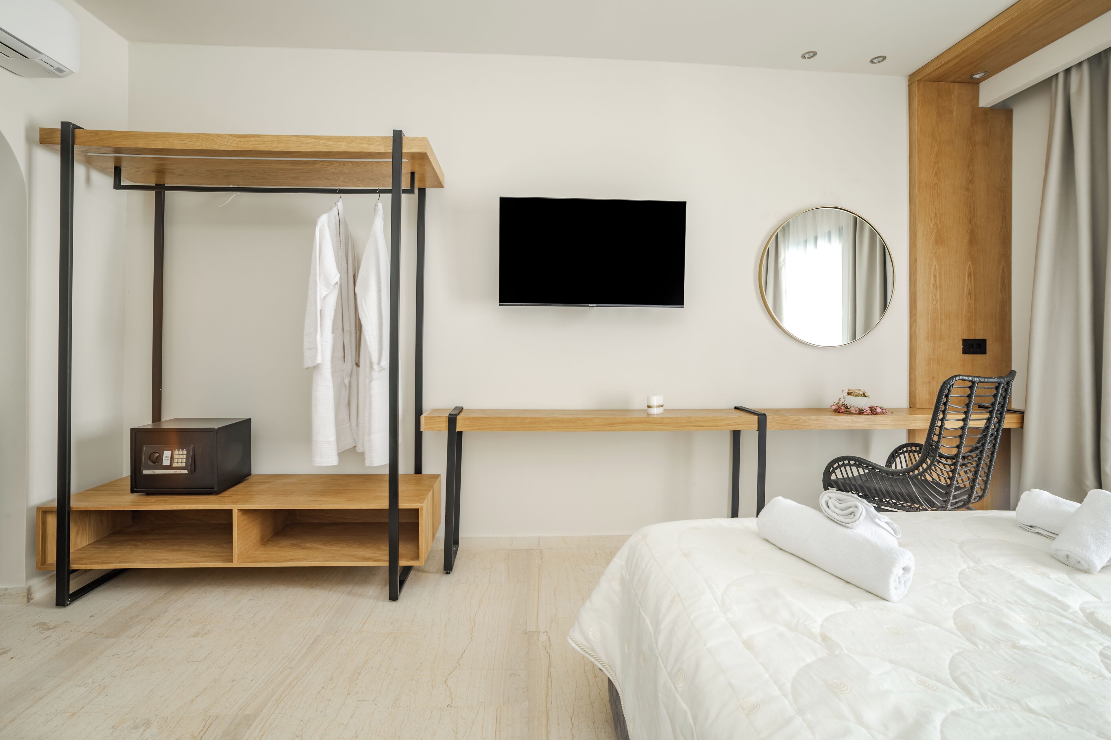 A modern hotel room with a bed, a desk, a chair, a TV, and a wardrobe.