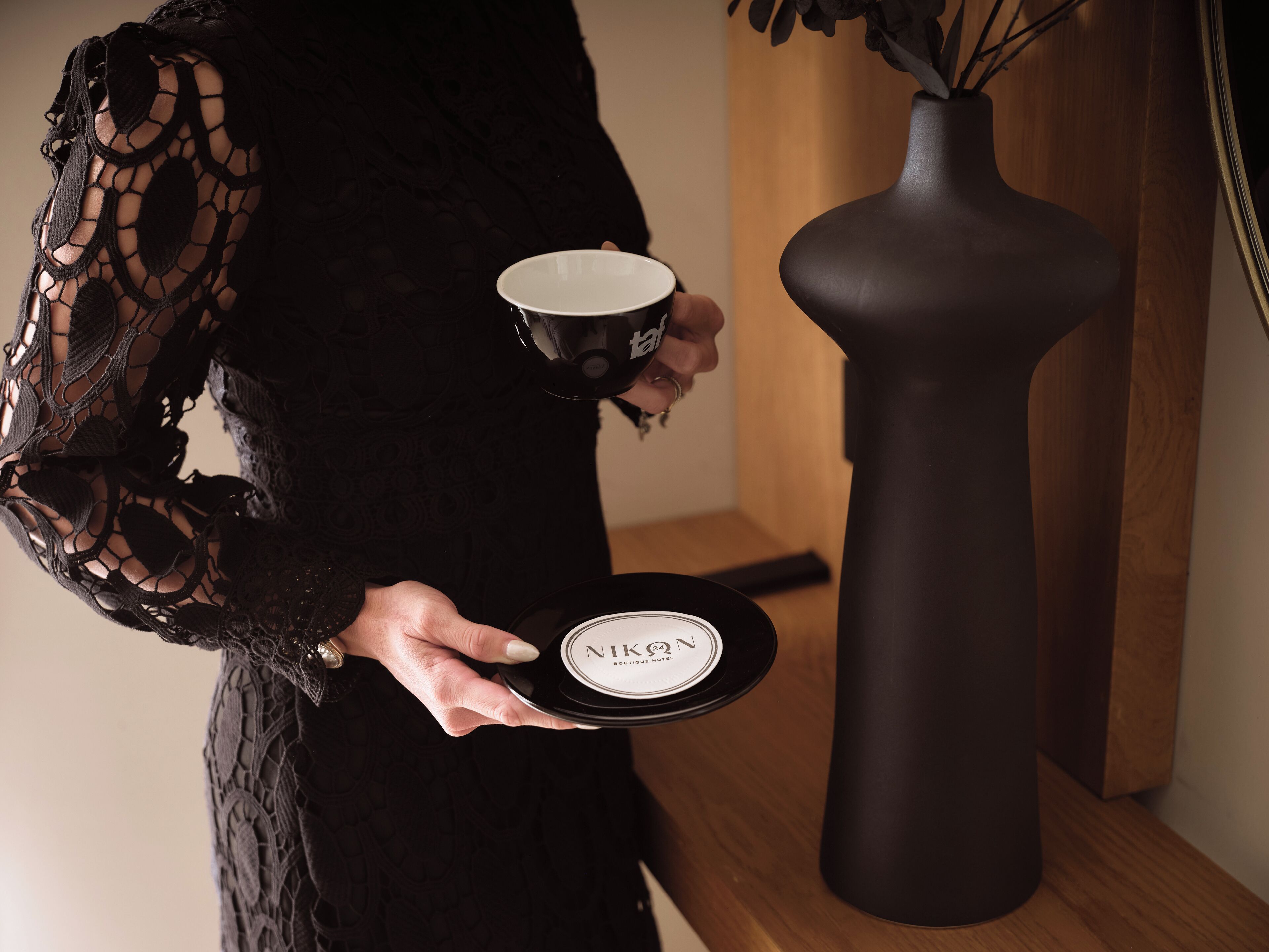 A person holding a black plate with a white label and a black cup.