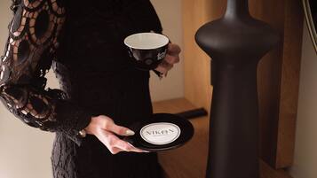 A person holding a black plate with a white label and a black cup.