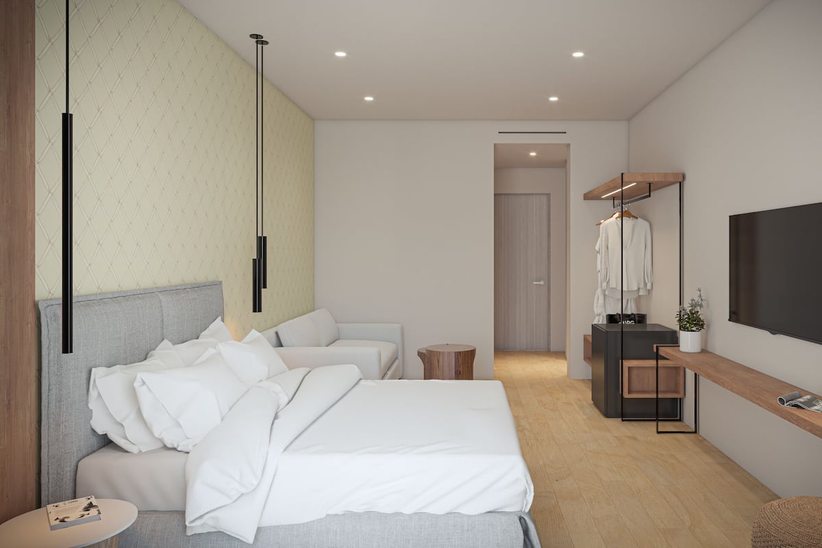 A modern hotel room with a large bed, a desk with a TV, and a wardrobe.
