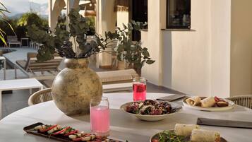 A table set with food, a vase with greenery, and a glass of pink drink.