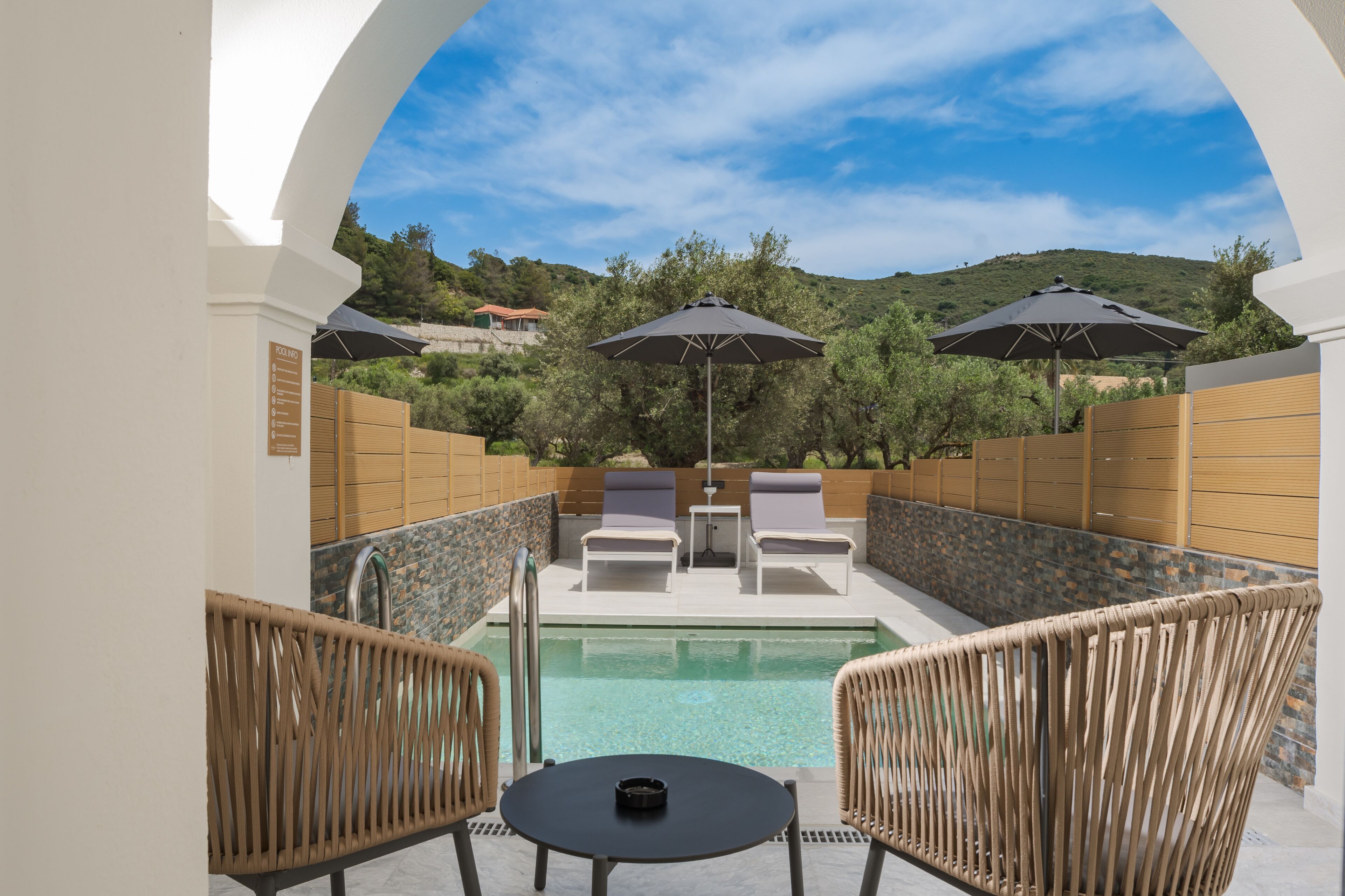 A poolside area with lounge chairs, umbrellas, and a table.