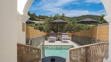 A poolside area with lounge chairs, umbrellas, and a table.
