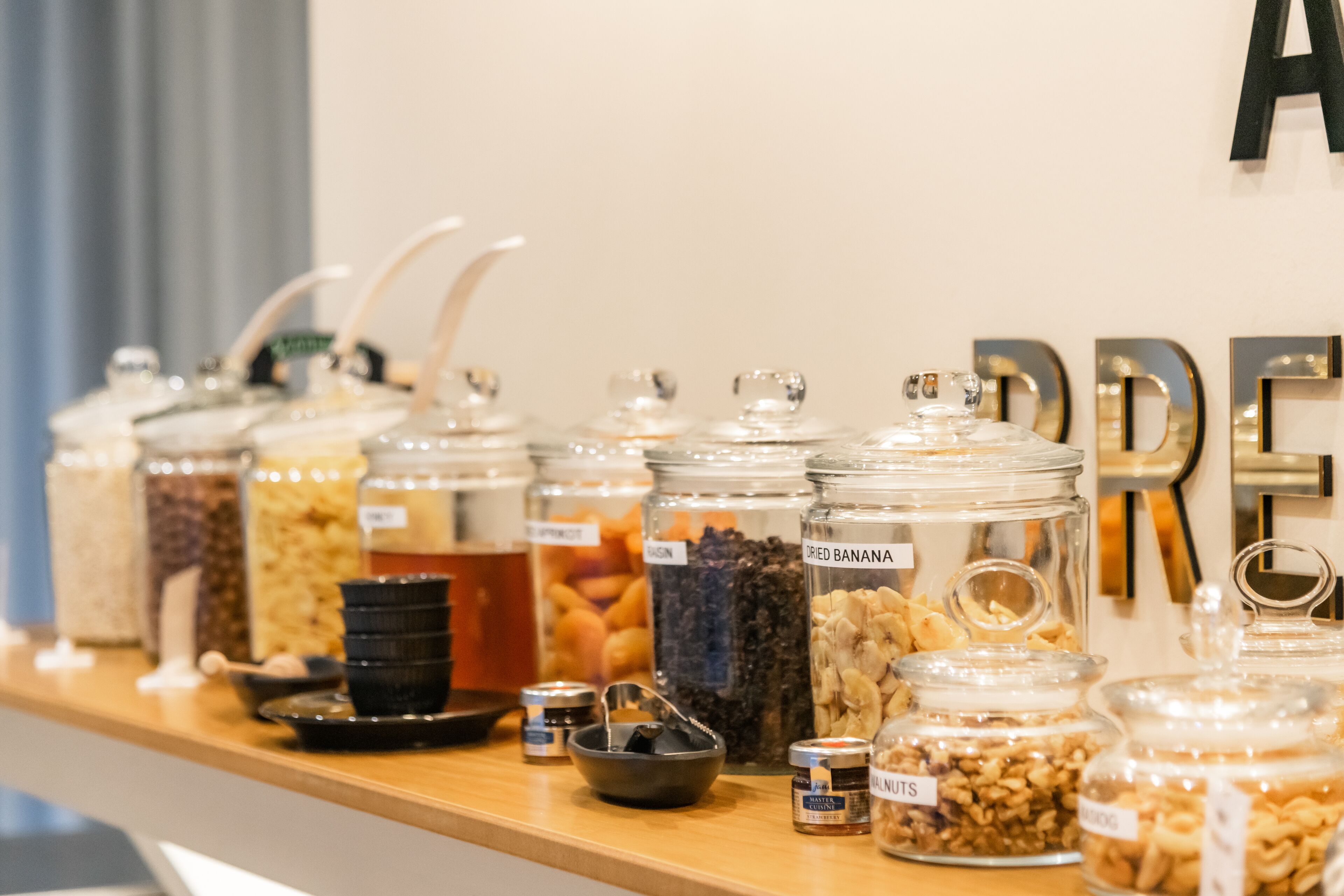 A food display with various jars labeled with contents like 'Dried Banana' and 'Almonds'.