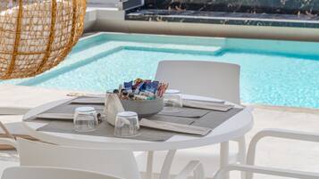 A poolside table with a bowl of snacks, glasses, and a hanging chair.