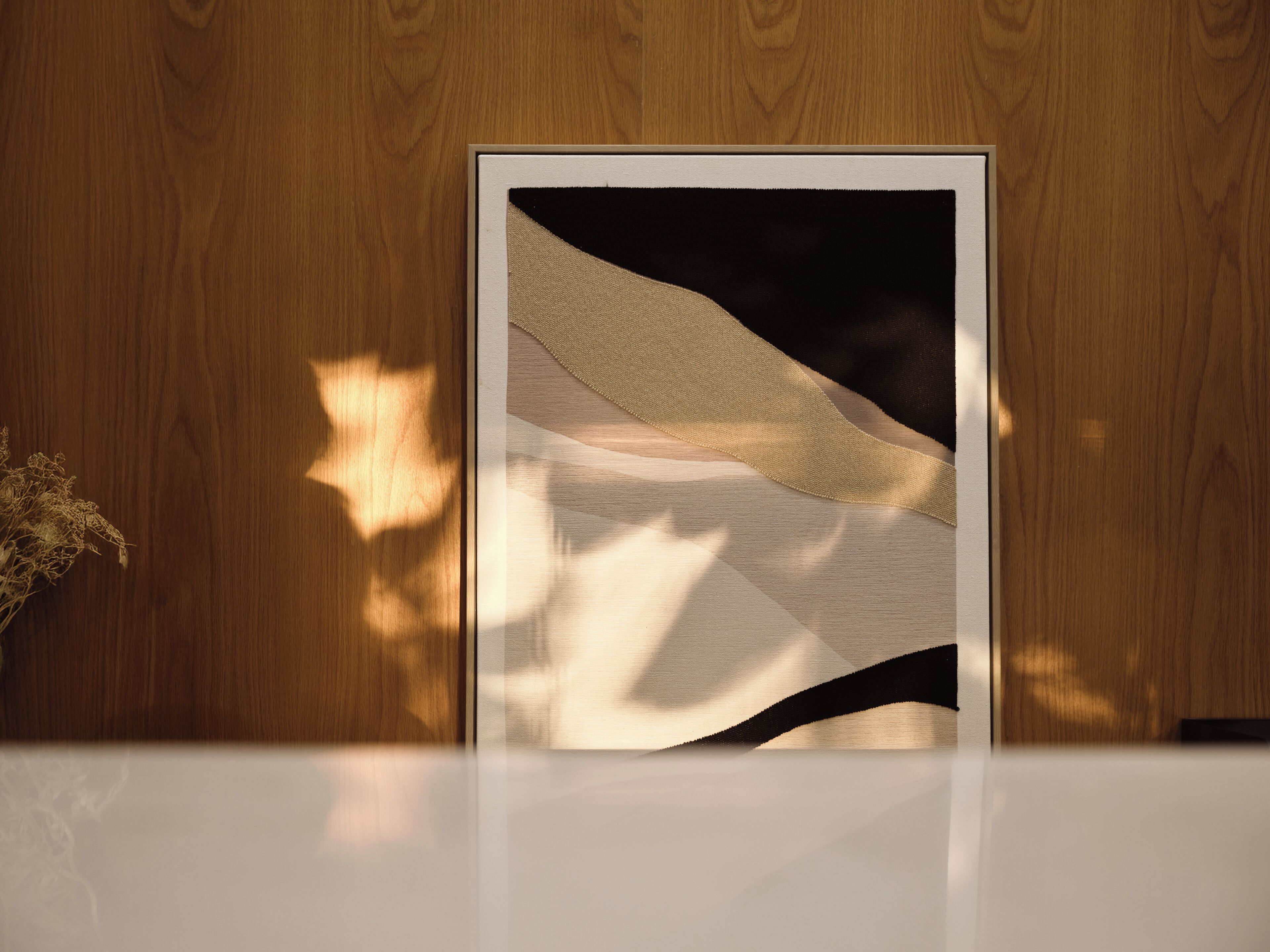 Una obra de arte enmarcadas con motivos abstractos sobre una pared de madera.