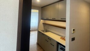 A modern kitchen with a built-in oven, a sink, and a window with blinds. - Nevi Hotel & Suites İstanbul Taksim (Istanbul)