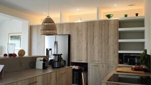 A modern kitchen with wooden cabinetry, a built-in island, and a hanging light fixture. - 5 min walk from beaches: modern villa ideally located. Piscine vue mer(Gigaro) (La Croix-Valmer)