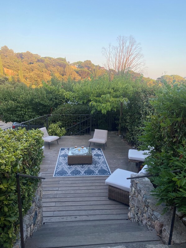 A wooden deck with outdoor furniture, a glass-top table, and a stone wall. - A 5-minute walk from the beaches: a modern villa in an ideal location. Pool with a view of the ocean (Gigaro) (La Croix-Valmer)