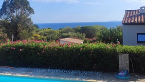 A swimming pool with clear blue water, surrounded by a stone patio, and a view of the sea and a building with a tiled roof. - 5 min walk from beaches: modern villa ideally located. Piscine vue mer(Gigaro) (La Croix-Valmer)
