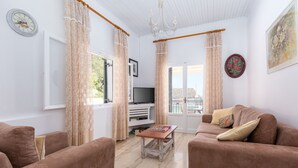Ein Wohnzimmer mit zwei braunen Sofas, einem kleinen Tisch, einem Fernseher und einem Fenster mit Vorhängen.