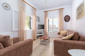 A living room with two brown sofas, a small table, a TV, and a window with curtains.