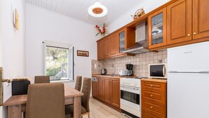 Eine Küche mit Holzausstattung, einem Herd, einer Mikrowelle und einem Essbereich mit Stühlen und einem Tisch.