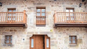 Un bâtiment en pierre doté de balcons en bois et d’une porte d’entrée en bois située au centre.