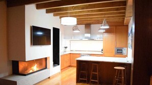 Une cuisine moderne dotée d’une cheminée intégrée, de meubles en bois et d’un coin bar avec des tabourets.