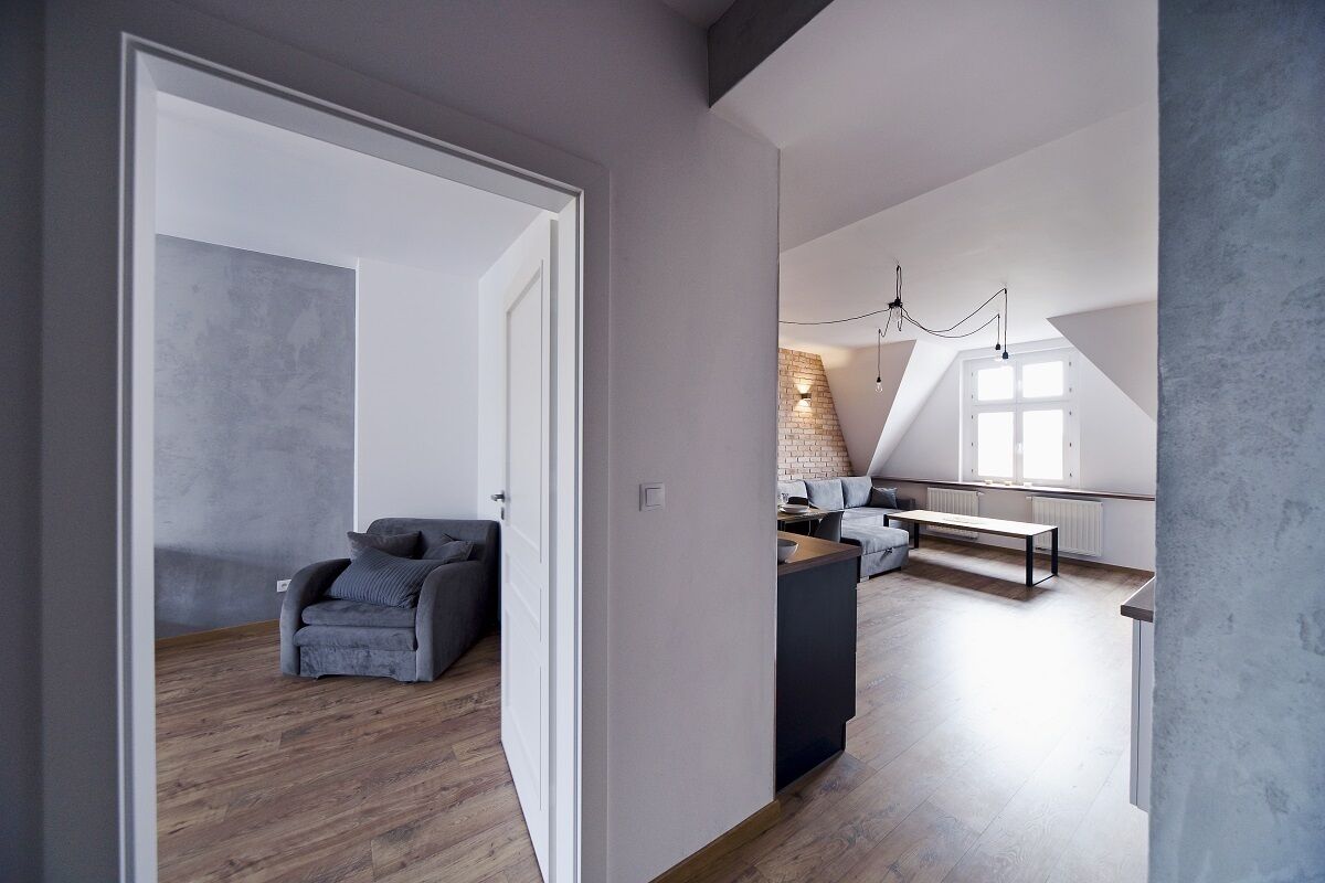 Un loft spacieux avec de hauts plafonds, un coin salon confortable avec un canapé et un fauteuil, et une table à manger.
