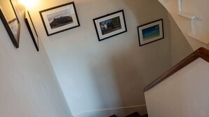 Un escalier avec une rampe en bois, des murs blancs et trois tableaux encadrés.