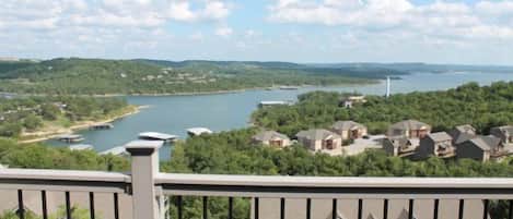 Un barrio residencial con casas, un lago y una turbina eólica a lo lejos.