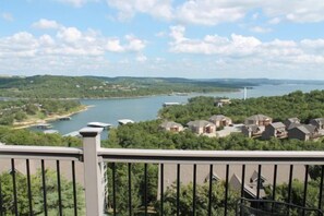 Un quartier résidentiel avec des maisons, un lac et une éolienne visible au loin.